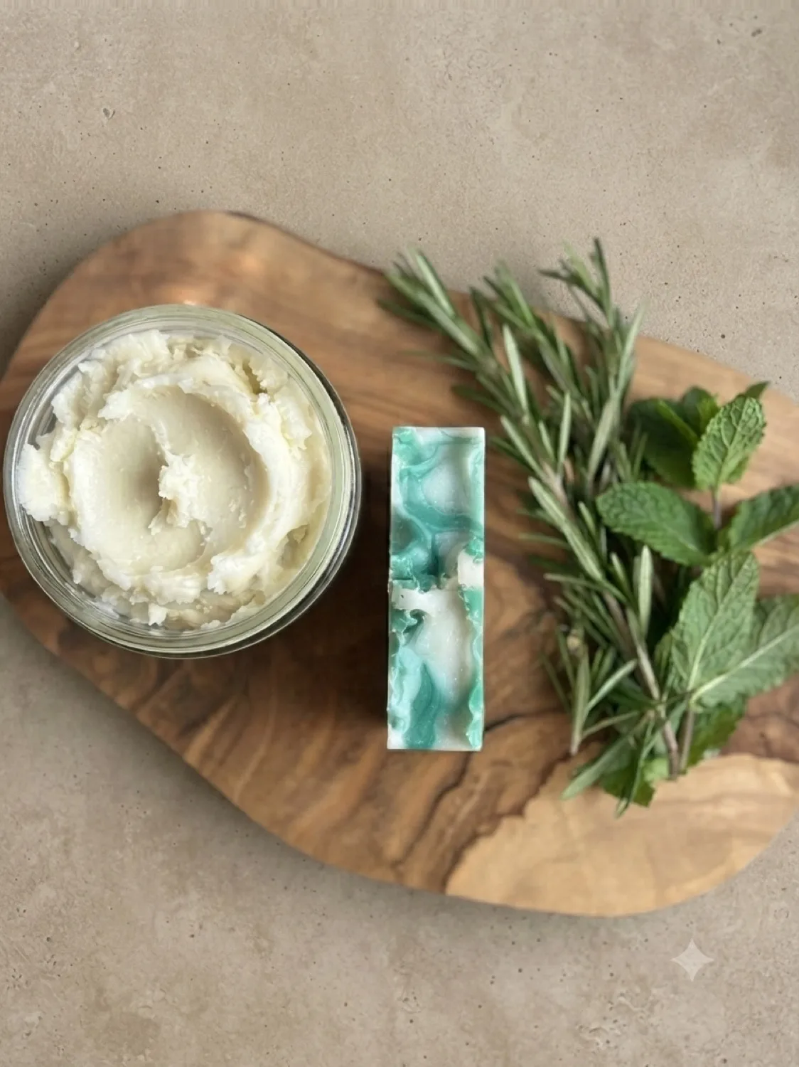 Overhead view of Foliage & Fronds soap, whipped body butter, rosemary and mint on a wooden board