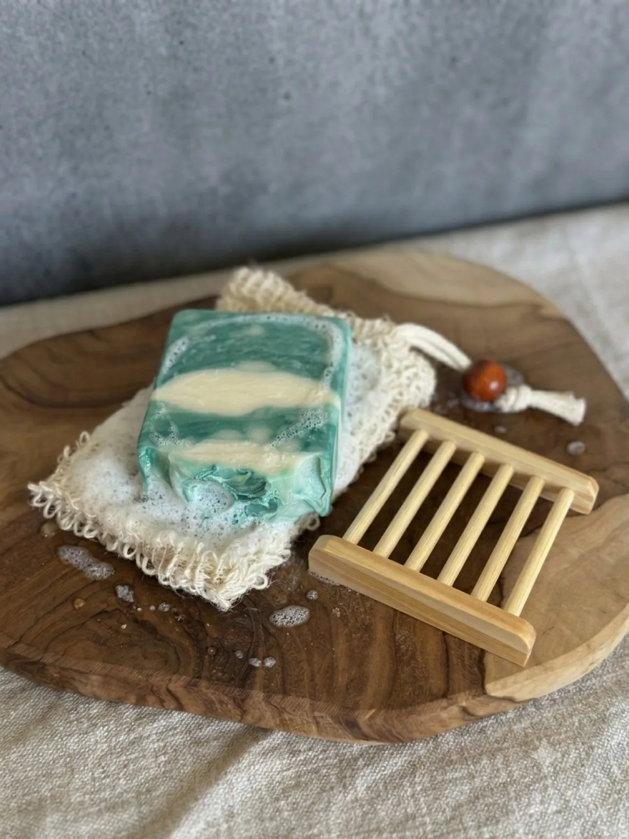 Foliage & Fronds botanical soap bar resting on a lather-covered sisal pouch beside a wooden soap dish